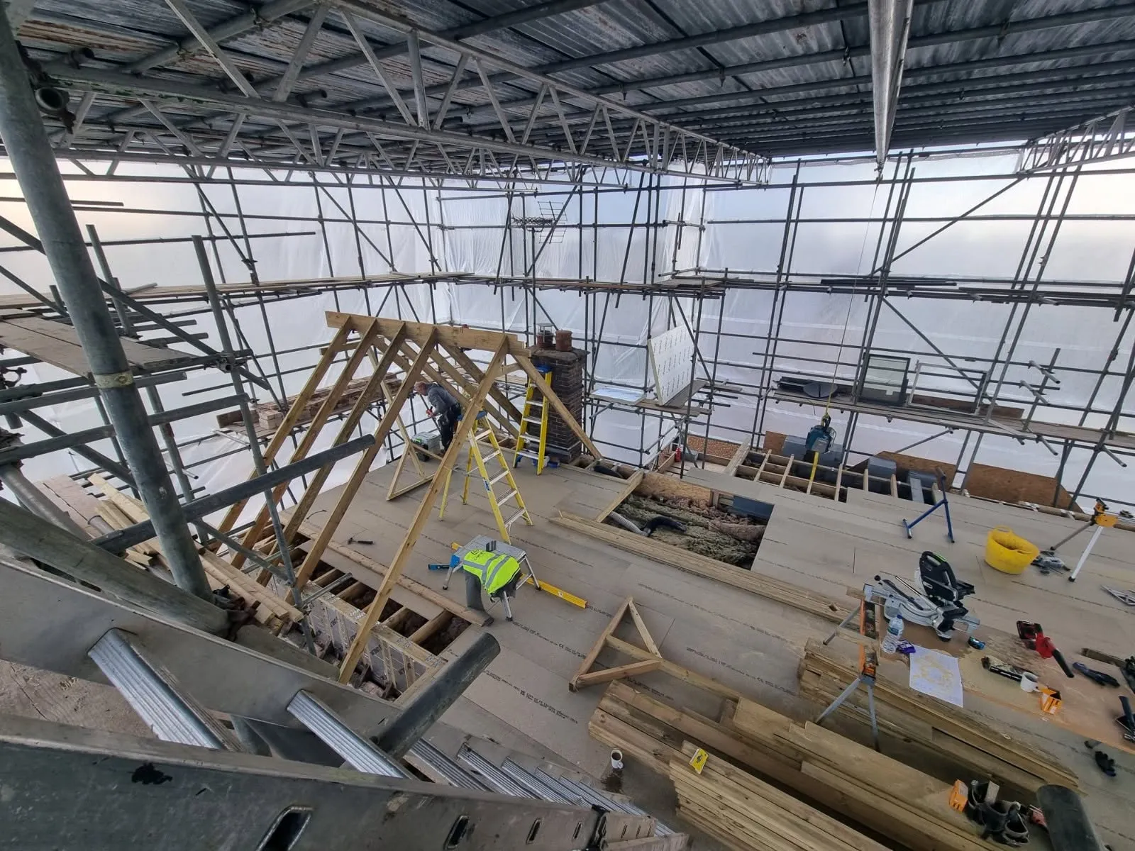Loft conversion in Pontypridd: new roof structure going up under a full scaffold cover — All Aspects Construction